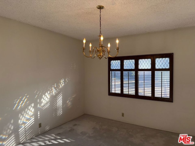 empty room with a chandelier, a textured ceiling, and carpet floors