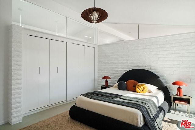 bedroom featuring multiple closets and brick wall