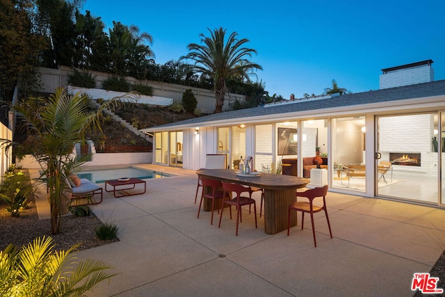 patio terrace at dusk with a fenced in pool