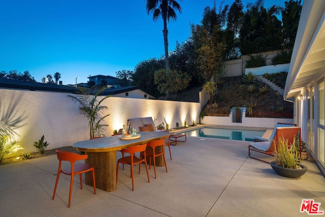 patio terrace at dusk featuring a fenced in pool