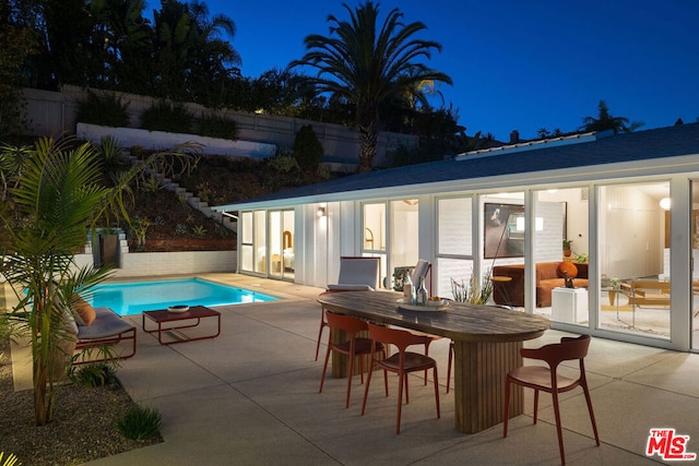 pool at night featuring a patio and exterior bar