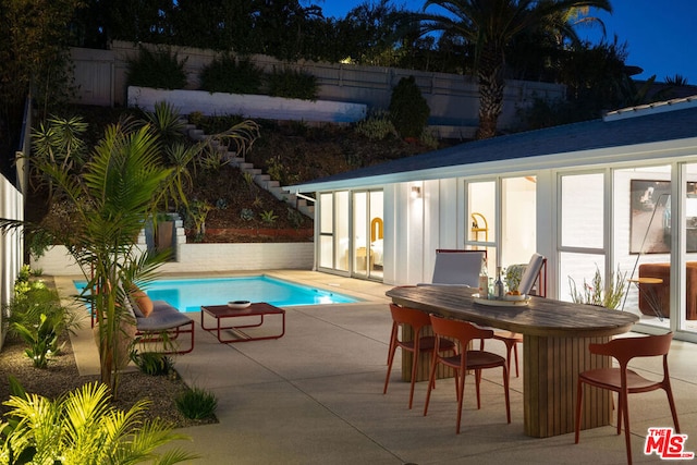 view of pool featuring a bar, an outbuilding, and a patio area