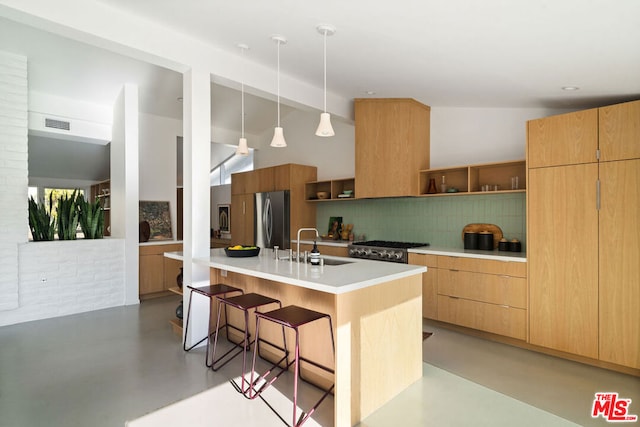 kitchen with stainless steel fridge, sink, backsplash, a kitchen bar, and a kitchen island with sink