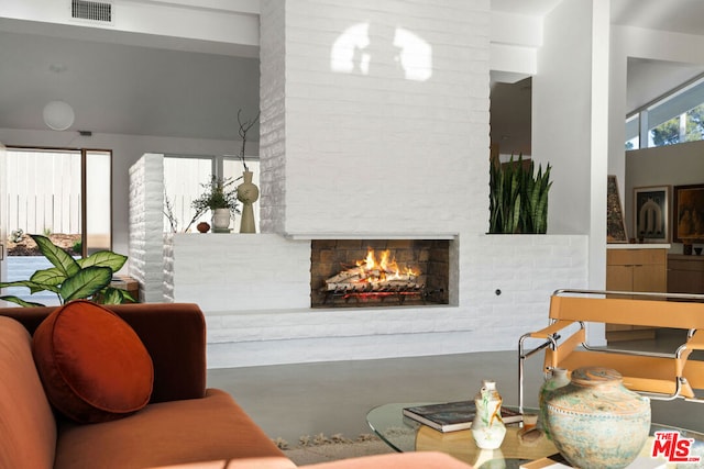 living room with concrete floors and a brick fireplace