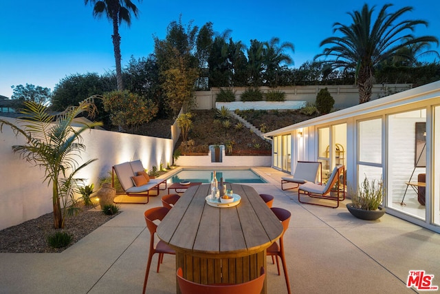 patio terrace at dusk featuring a fenced in pool