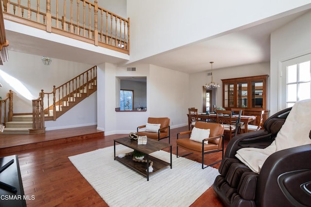 living room with a notable chandelier, dark hardwood / wood-style floors, a high ceiling, and a wealth of natural light