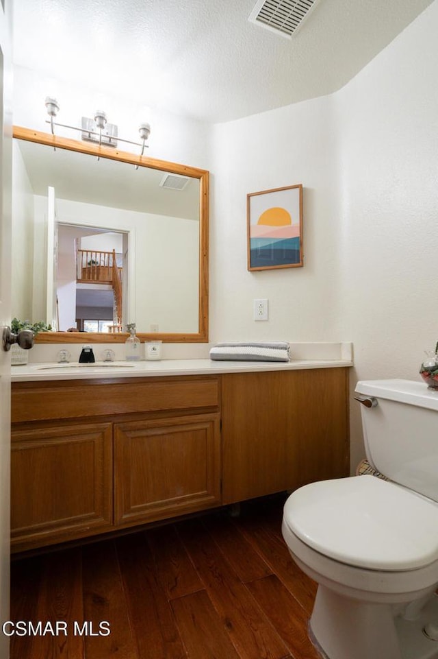 bathroom featuring vanity, toilet, hardwood / wood-style floors, and a textured ceiling