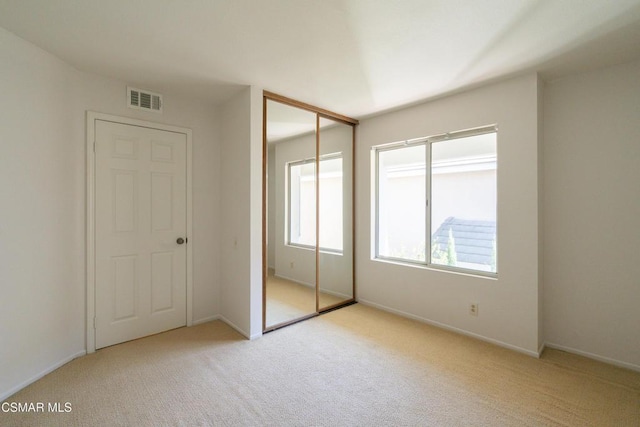 unfurnished bedroom featuring light colored carpet and a closet