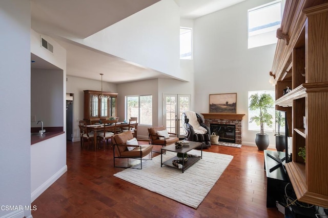 living room featuring french doors, dark wood-type flooring, sink, a fireplace, and a high ceiling