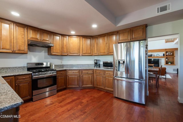 kitchen featuring stainless steel appliances, light stone counters, and dark hardwood / wood-style flooring