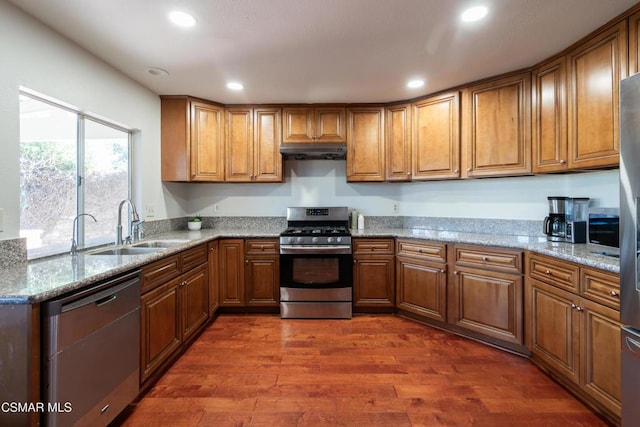 kitchen with light stone counters, sink, dark hardwood / wood-style flooring, and stainless steel appliances