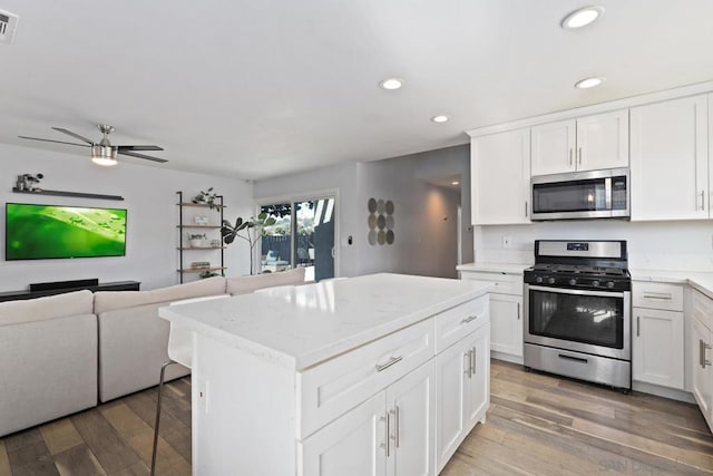 kitchen with white cabinets, hardwood / wood-style flooring, a center island, and appliances with stainless steel finishes