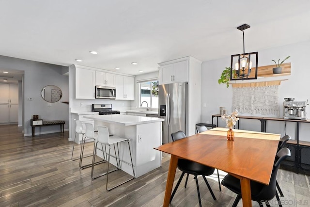 kitchen with appliances with stainless steel finishes, white cabinetry, hanging light fixtures, sink, and dark wood-type flooring