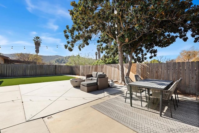 view of patio with a mountain view and an outdoor living space with a fire pit