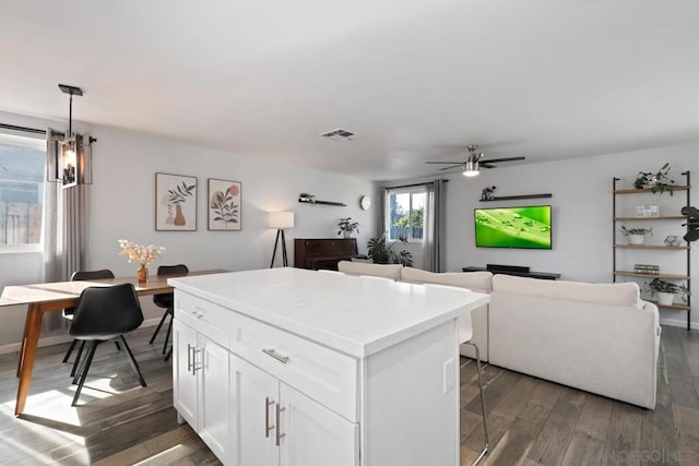 kitchen with white cabinets, a kitchen island, pendant lighting, a breakfast bar, and dark hardwood / wood-style floors