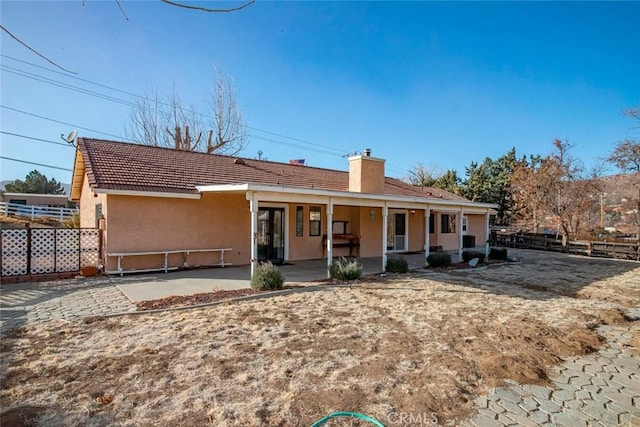 rear view of property with covered porch and a patio