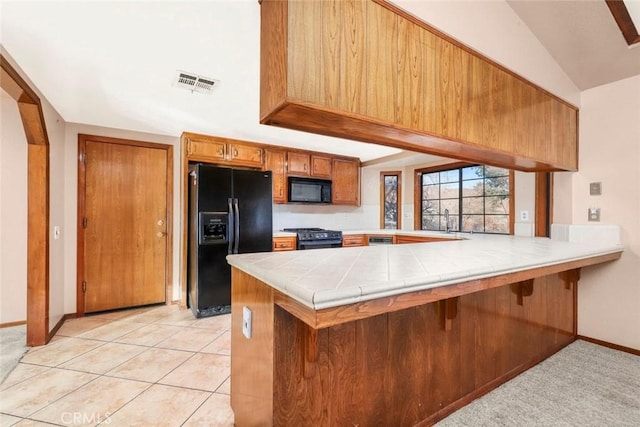 kitchen featuring black appliances, tile counters, light tile patterned floors, sink, and kitchen peninsula