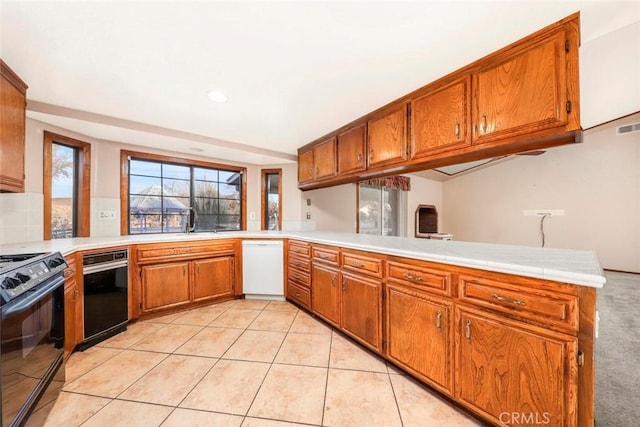 kitchen featuring kitchen peninsula, dishwasher, sink, black stove, and light tile patterned floors