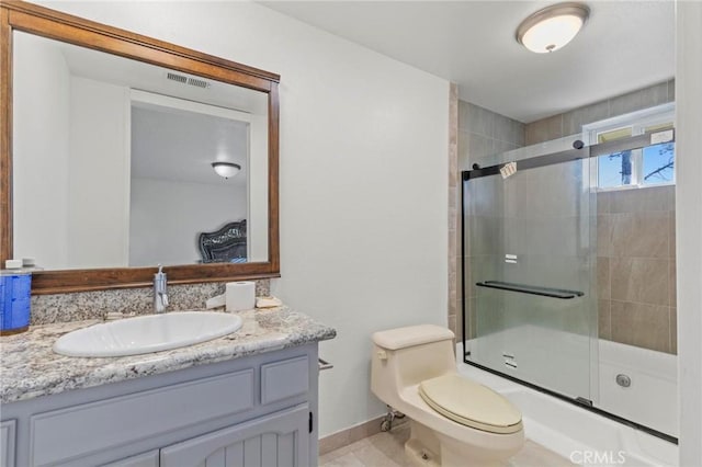 full bathroom with bath / shower combo with glass door, tile patterned floors, vanity, and toilet