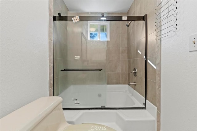 bathroom featuring shower / bath combination with glass door and toilet