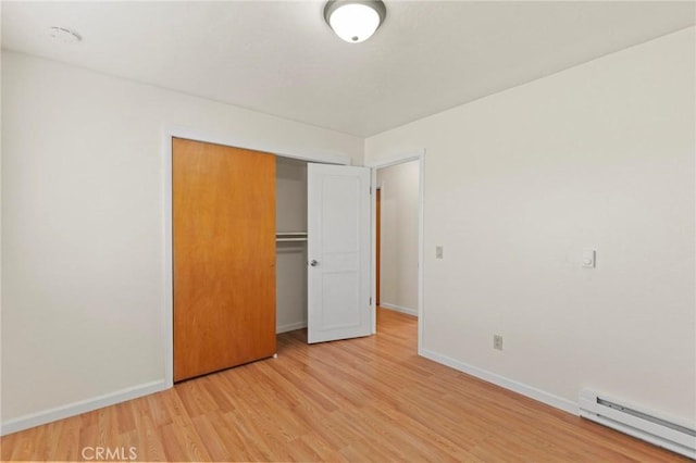 unfurnished bedroom featuring light hardwood / wood-style flooring, a closet, and baseboard heating