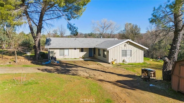 back of house featuring driveway, a yard, board and batten siding, and a shingled roof