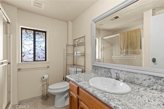 bathroom featuring vanity, toilet, an enclosed shower, and tile patterned flooring