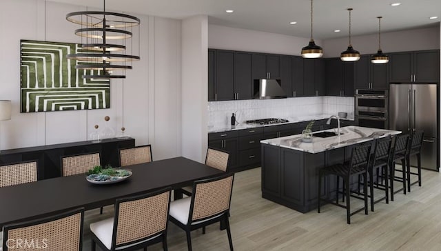 kitchen featuring light hardwood / wood-style floors, light stone countertops, pendant lighting, and stainless steel appliances