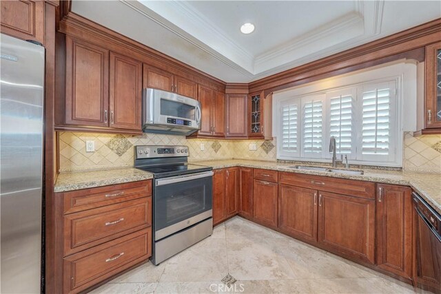 kitchen with sink, backsplash, light stone counters, and appliances with stainless steel finishes