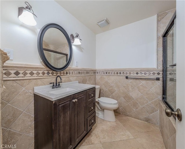 bathroom featuring tile walls, toilet, vanity, and tile patterned flooring