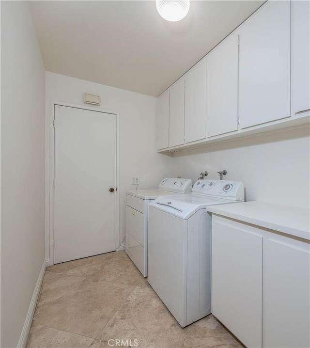 clothes washing area with separate washer and dryer and cabinets