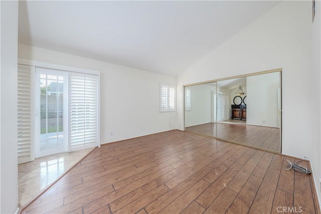 unfurnished room with hardwood / wood-style floors and high vaulted ceiling