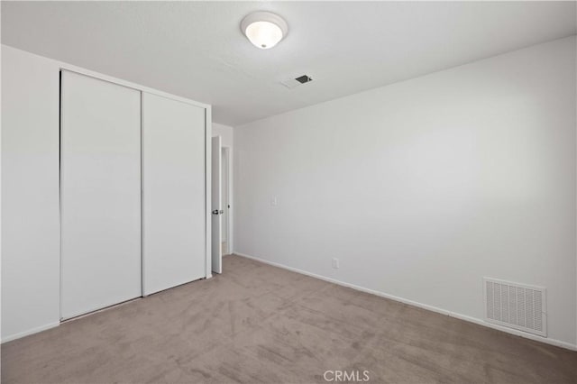 unfurnished bedroom with light carpet and a closet