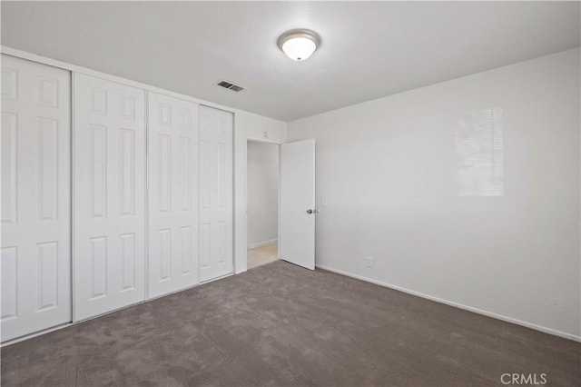 unfurnished bedroom featuring dark colored carpet and a closet