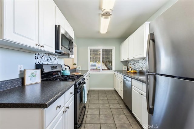 kitchen with stainless steel appliances, white cabinetry, dark tile patterned floors, and decorative backsplash