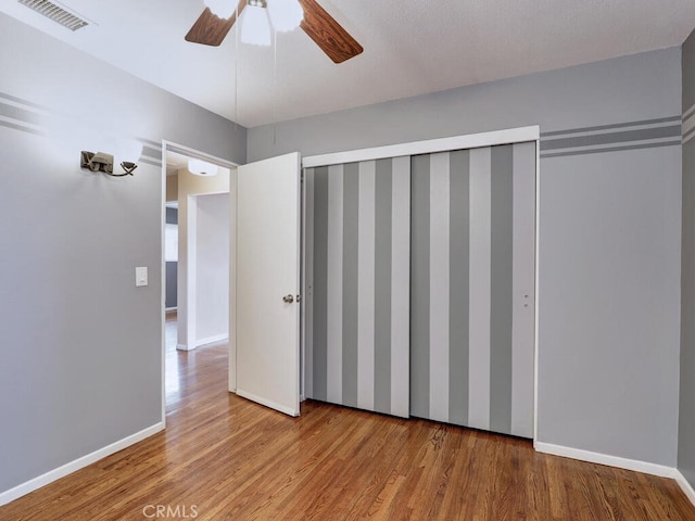 unfurnished bedroom featuring light wood-type flooring, ceiling fan, and a closet