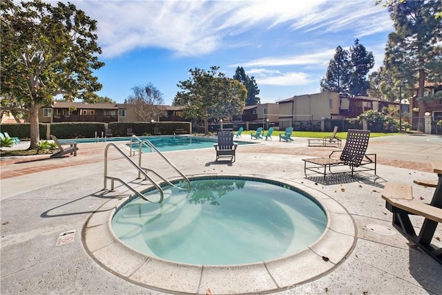 community pool featuring a patio area, a hot tub, and fence