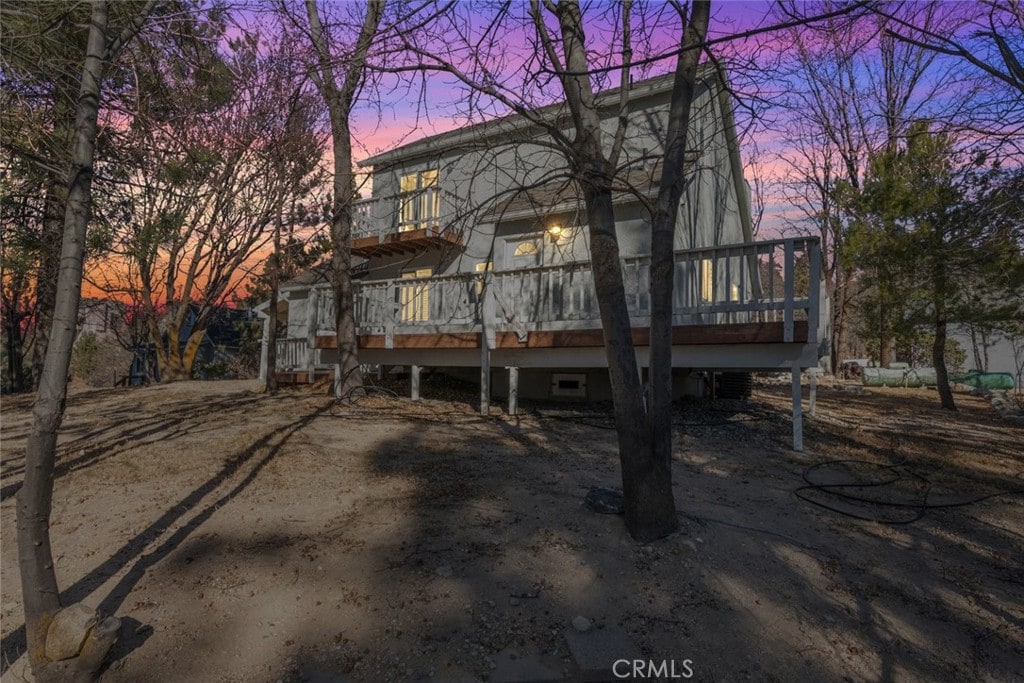 back house at dusk with a wooden deck