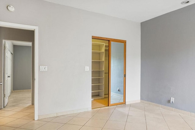 unfurnished bedroom with a closet, light tile patterned floors, and a spacious closet