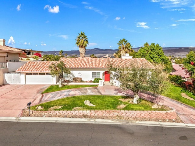 view of front of home with a garage, a mountain view, and a front yard