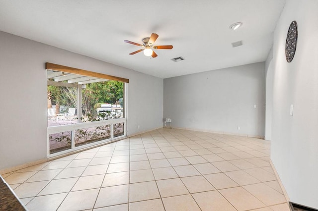 empty room with ceiling fan and light tile patterned floors