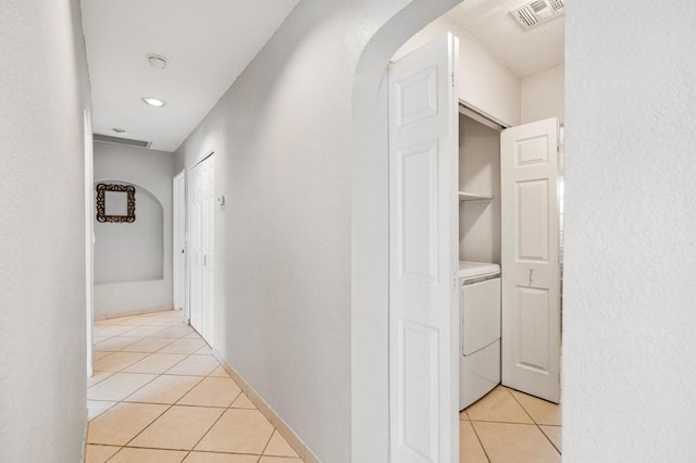 hallway with light tile patterned floors and washer / dryer