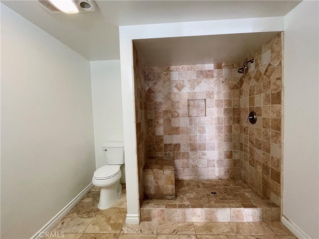 bathroom featuring tiled shower and toilet