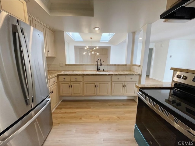 kitchen featuring sink, range hood, appliances with stainless steel finishes, and cream cabinetry