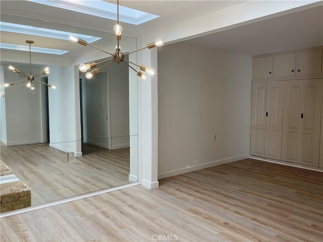 unfurnished room with light wood-type flooring, vaulted ceiling with skylight, and a notable chandelier