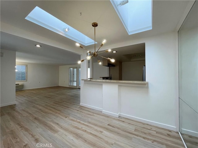 interior space with light hardwood / wood-style floors, a skylight, a chandelier, an AC wall unit, and pendant lighting