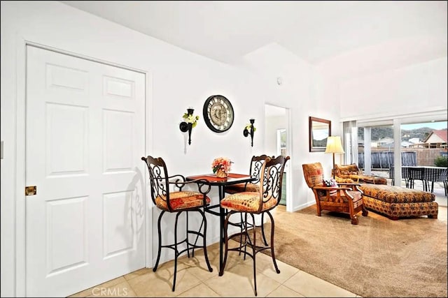 dining space featuring light carpet, baseboards, and light tile patterned floors