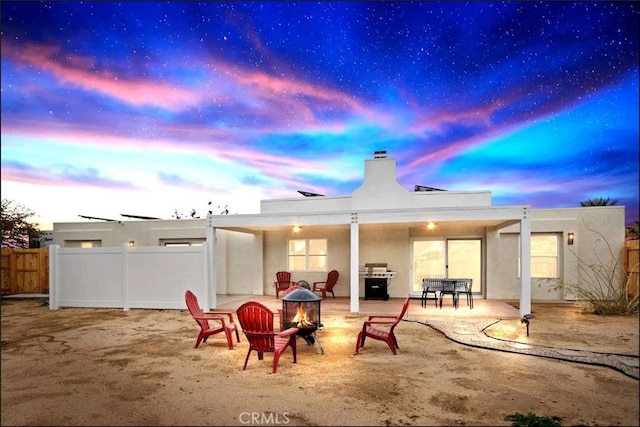 back house at dusk featuring a patio area and a fire pit