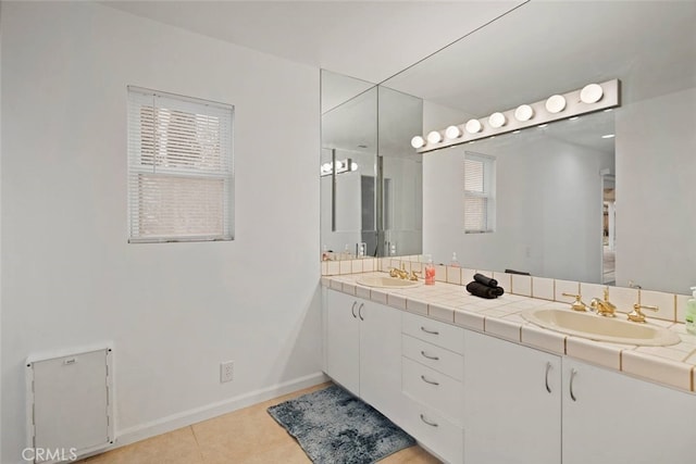 bathroom with baseboards, double vanity, a sink, and tile patterned floors