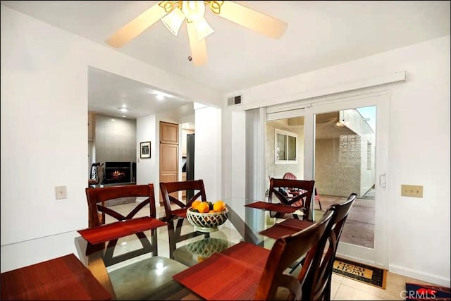 dining room with a large fireplace, visible vents, and a ceiling fan